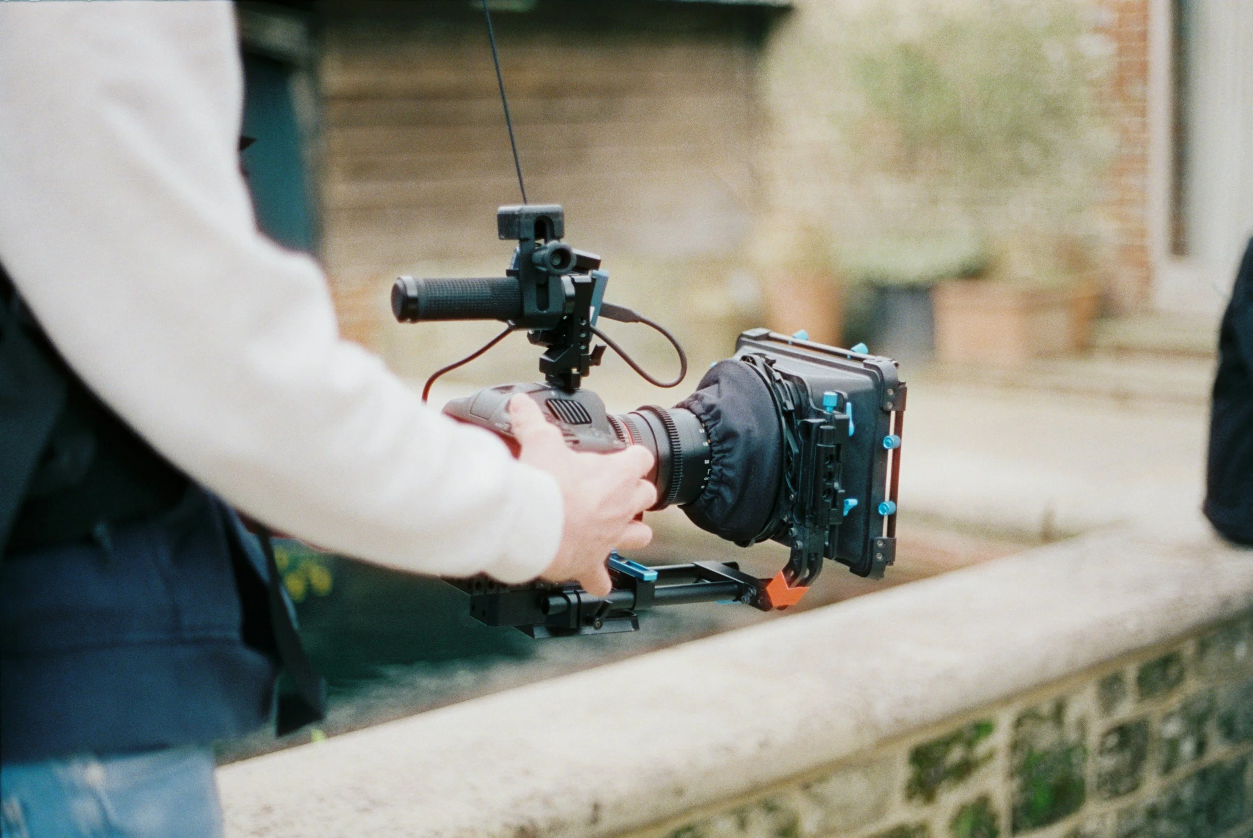 Persona manejando una cámara profesional con estabilizador en un entorno exterior urbano.