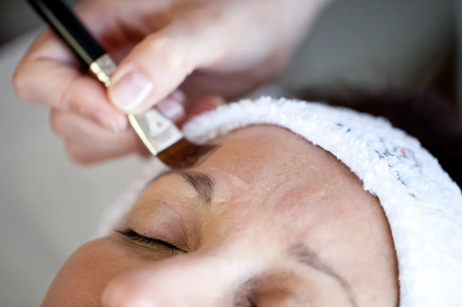 A person receiving a facial treatment with an alcohol wipe being