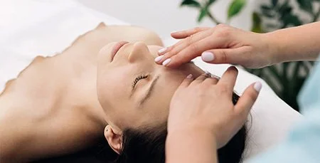 A woman receiving a facial massage in a spa setting