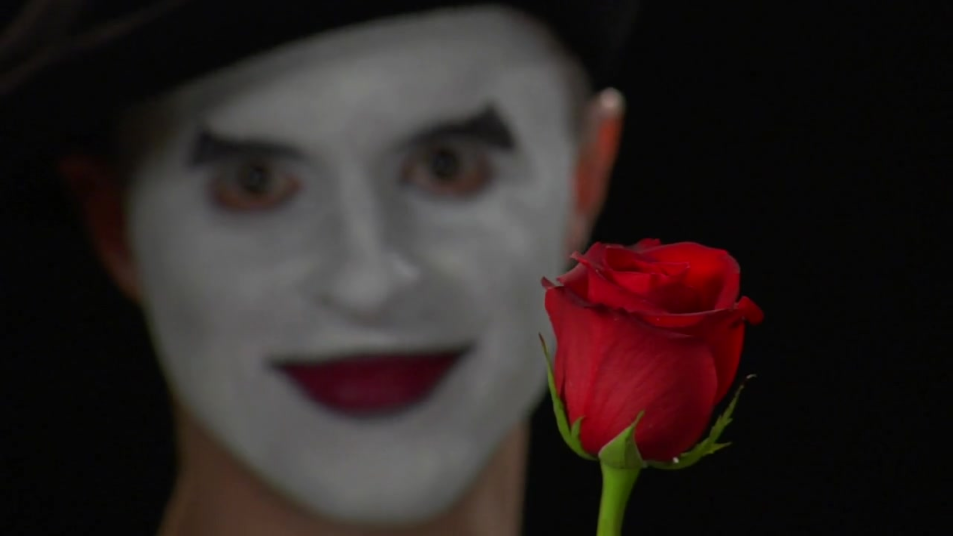 Man with dramatic white makeup holding red rose, Sweet Oblivion poem by Dawn Bratton