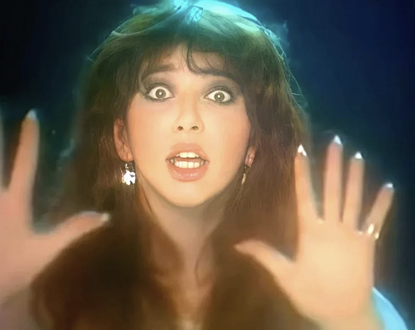Kate Bush performing with dramatic expression and outstretched hands, YouTube video still