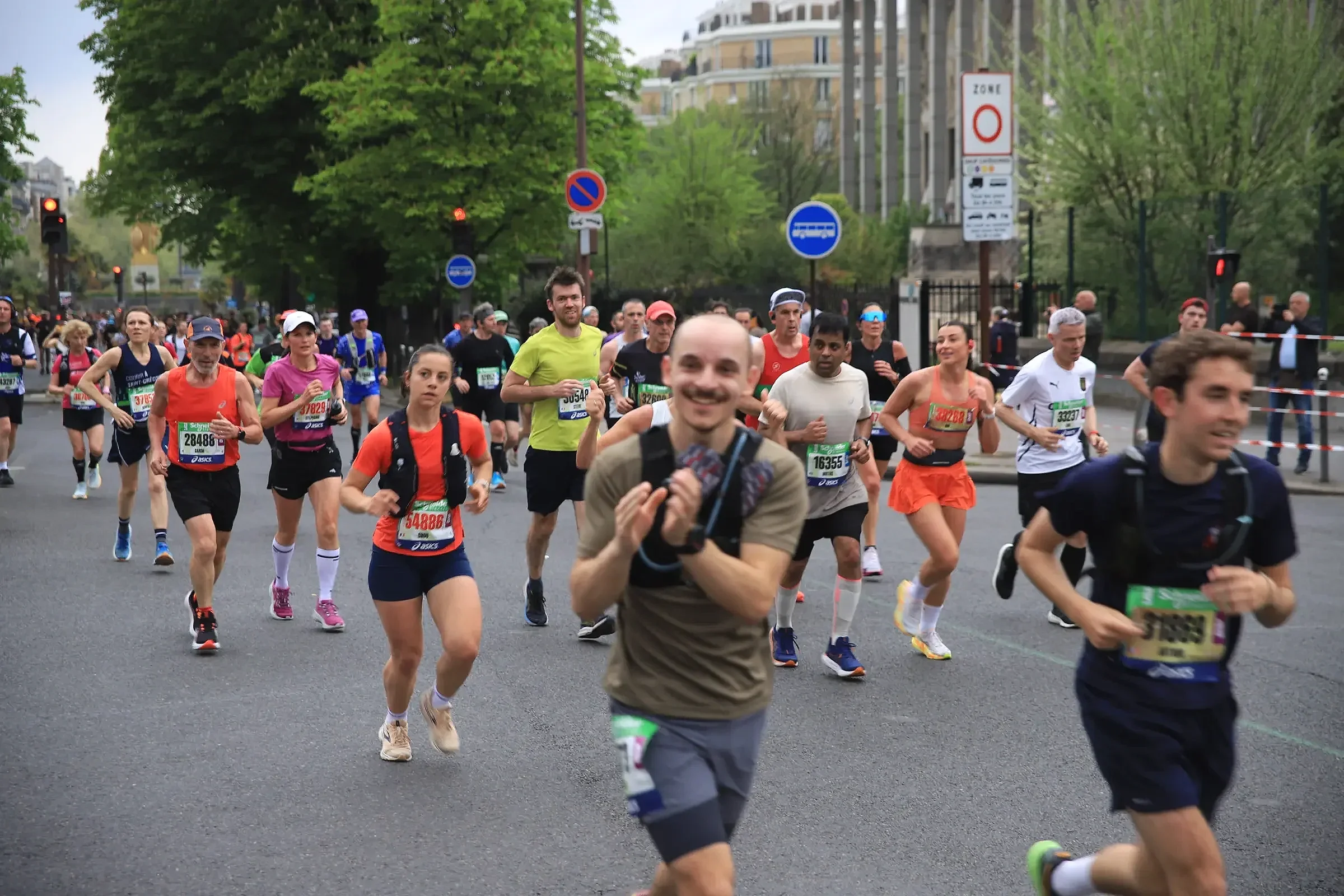 Plusieurs coureurs et coureuses en plein effort durant le Marathon de Paris, illustrant l'ambiance et l'ampleur de l'événement sportif. Photo : Studio Olympe