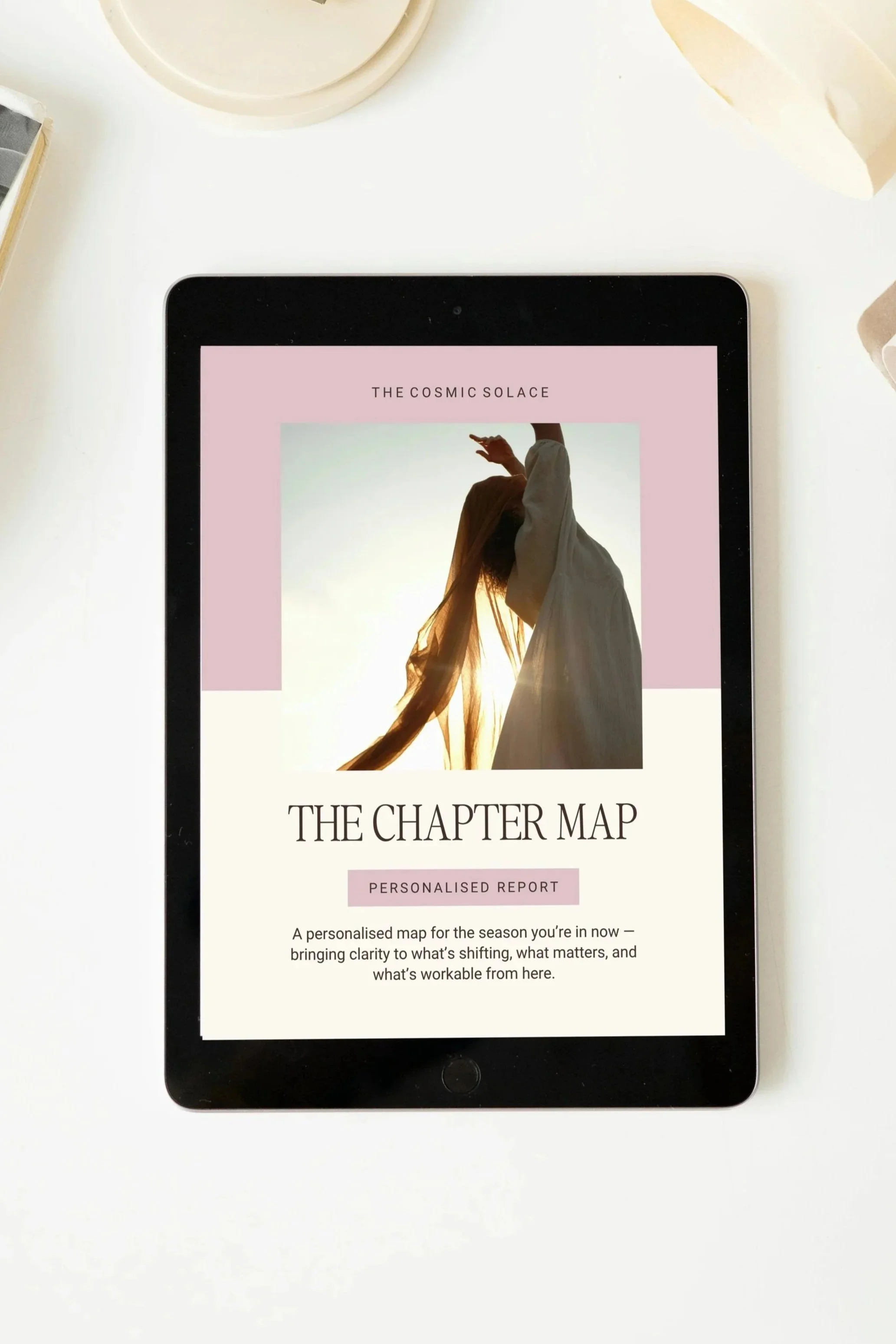 A digital tablet displays a report titled "The Chapter Map" with a subtitle "Personalised Report" and an image of a woman with long hair, wearing flowing clothing, raising her hand with the sun setting behind her.