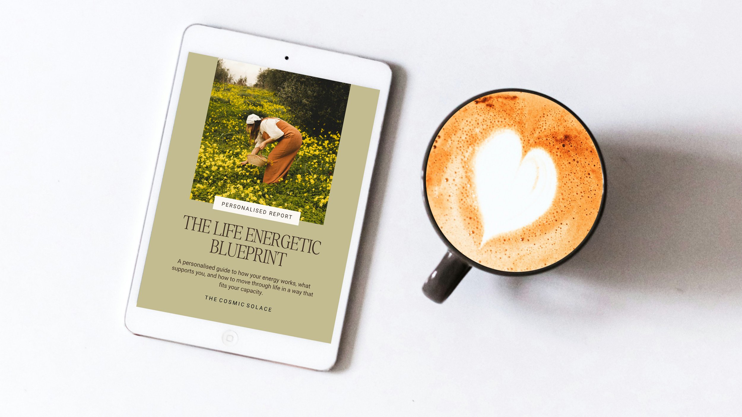A white tablet displaying a report titled 'The Life Energetic Blueprint' with a cover photo of a woman in a field of yellow flowers. Next to it is a black mug filled with coffee topped with latte art in the shape of a heart on a white surface.