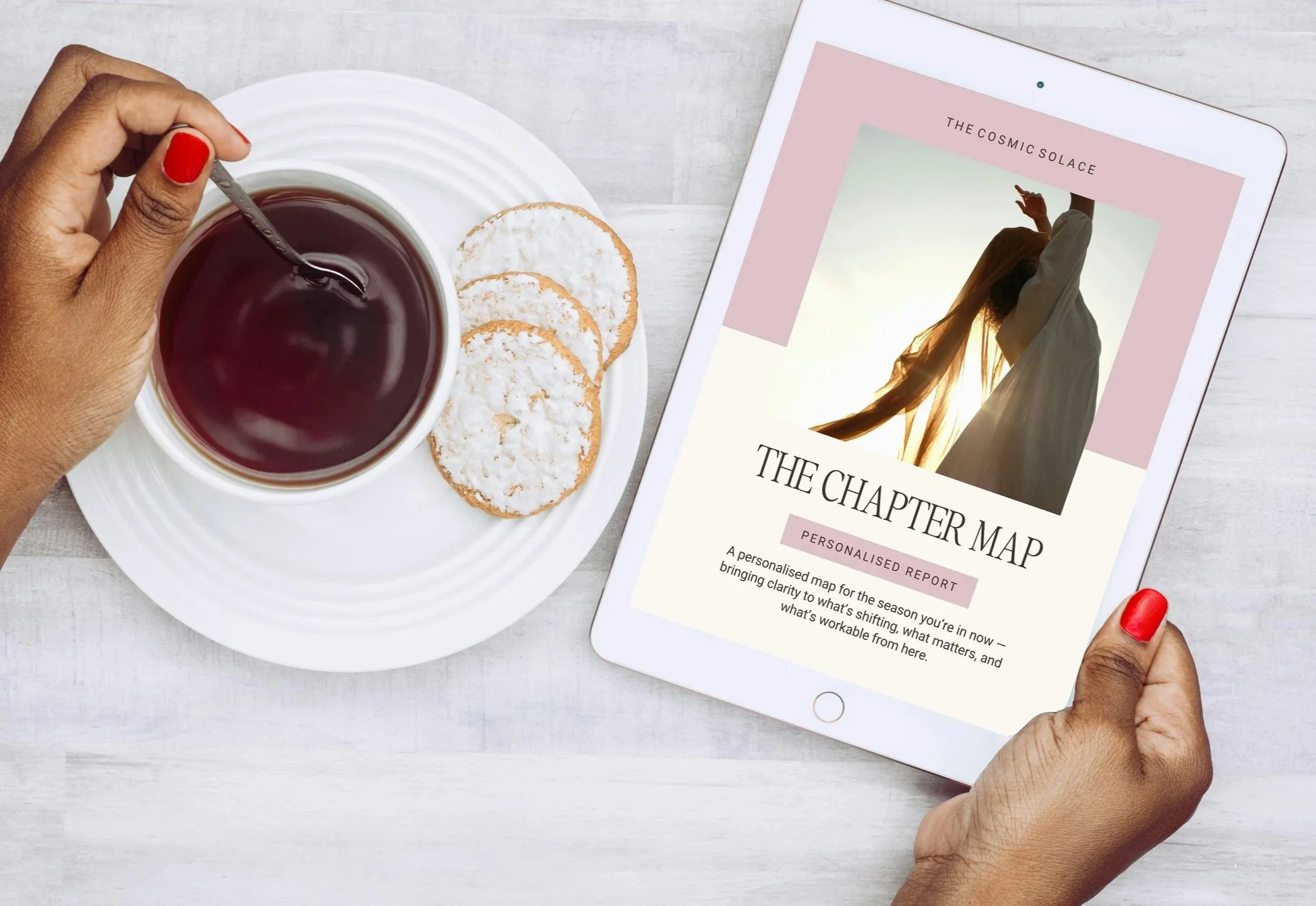 A person holding a tablet displaying a report called 'The Chapter Map' with a cover photo of a woman standing in front of a sunset. There is a cup of tea with a spoon and three cookies on a white plate nearby on a light-colored wooden table.