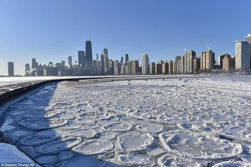 Chicago skyline with snow-covered lakefront in winter, with ice on the water and high-rise buildings in the distance.