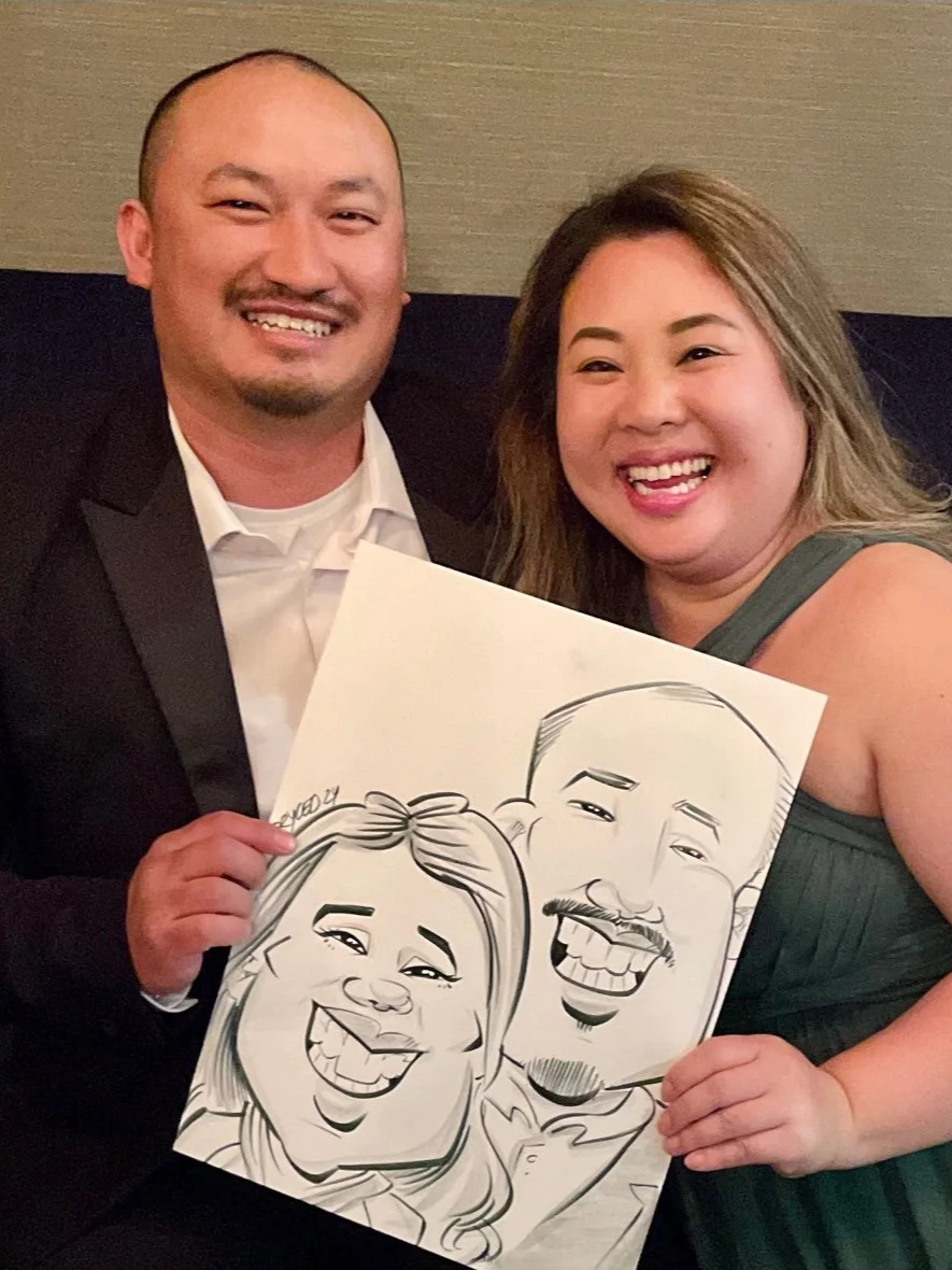 Formally dressed couple smiling and holding their live caricature drawing at an elegant gala event.