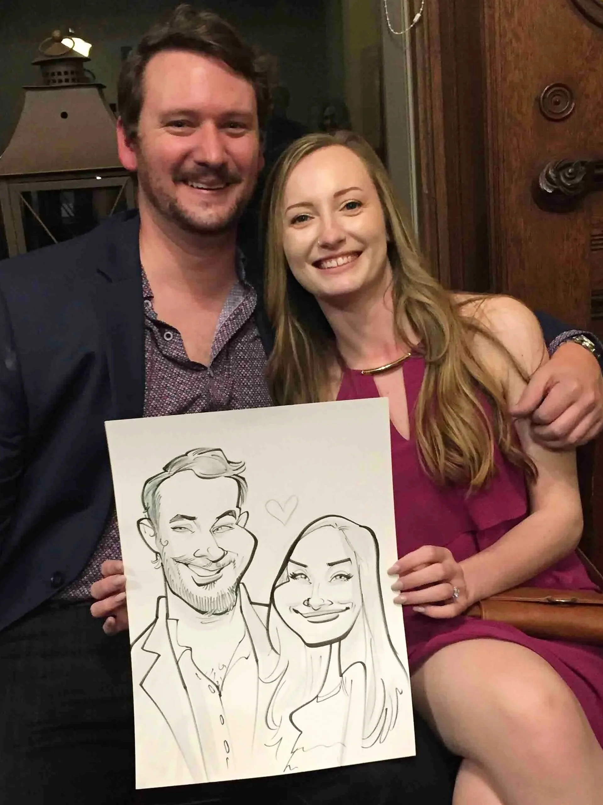 Couple seated together, smiling and holding their caricature portrait drawn live at a Minnesota event.