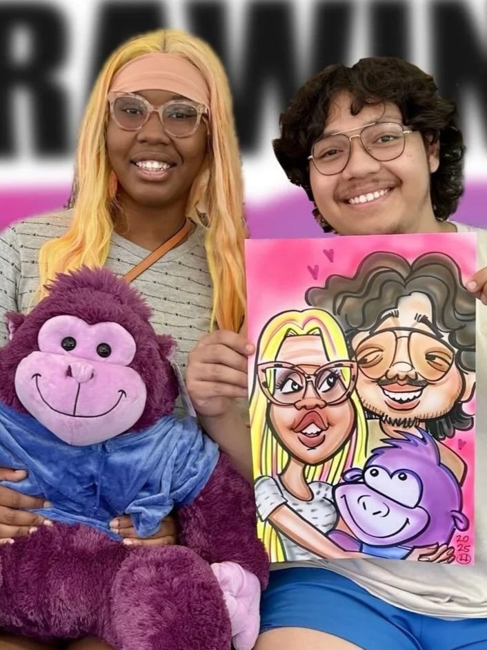 Couple holding a colorful caricature of themselves at a fun event, with a purple stuffed monkey toy in the foreground.
