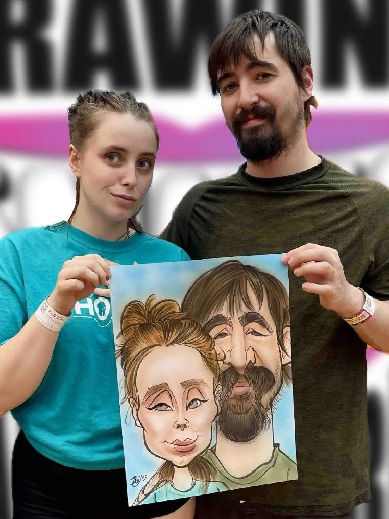Two people, a young woman and a man, holding a caricature portrait of themselves at an event.