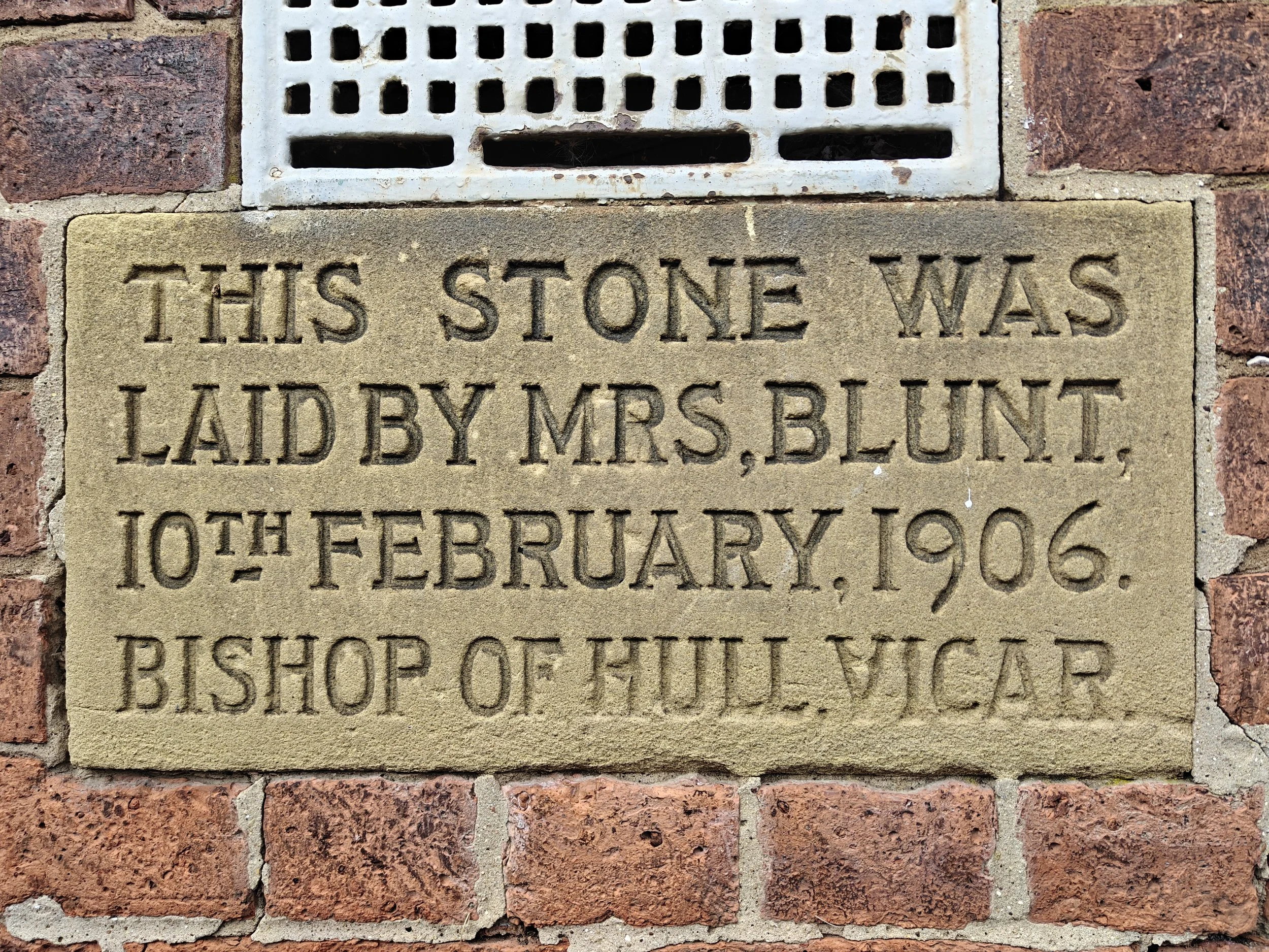 A cornerstone within a brick wall stating that the stone was laid by Mrs. Blunt, Bishop of Hull, on the 10th of February 1906.