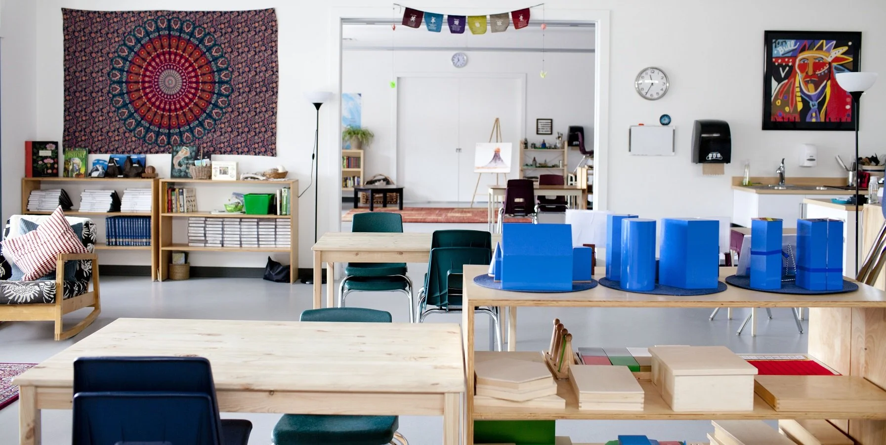 Montessori classroom with wooden tables, learning materials, and chairs arranged in a calm, bright environment at Skyridge Montessori.