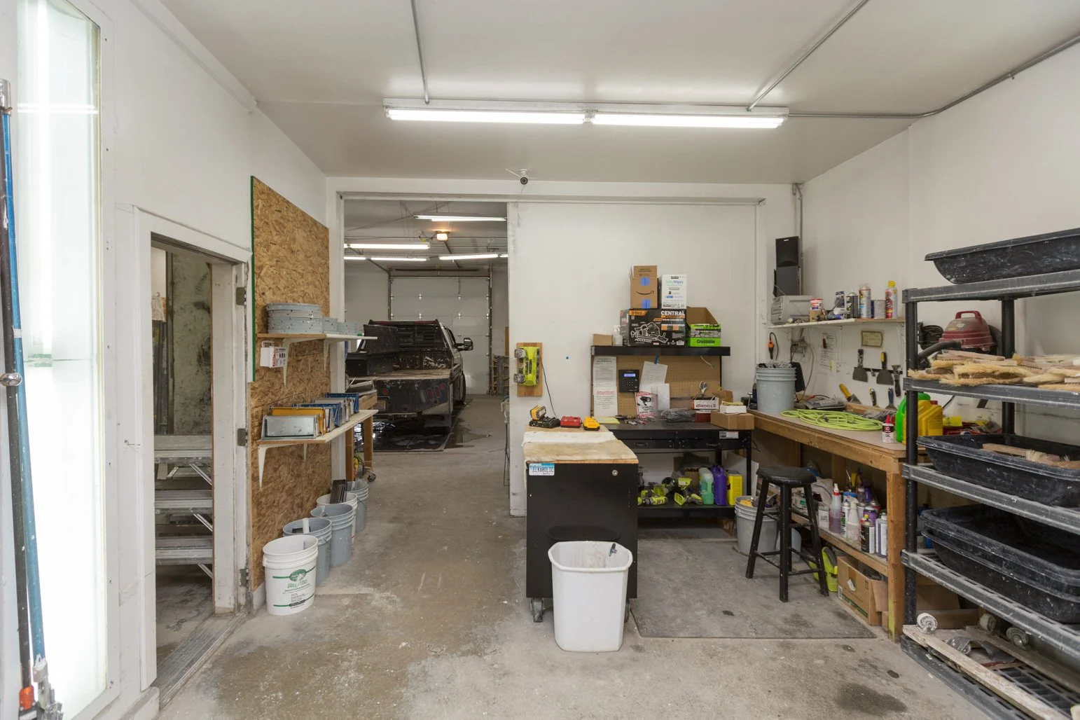 Olbricht workshop with shelves of tools, a workbench, and a vehicle in the background for repair or maintenance work.