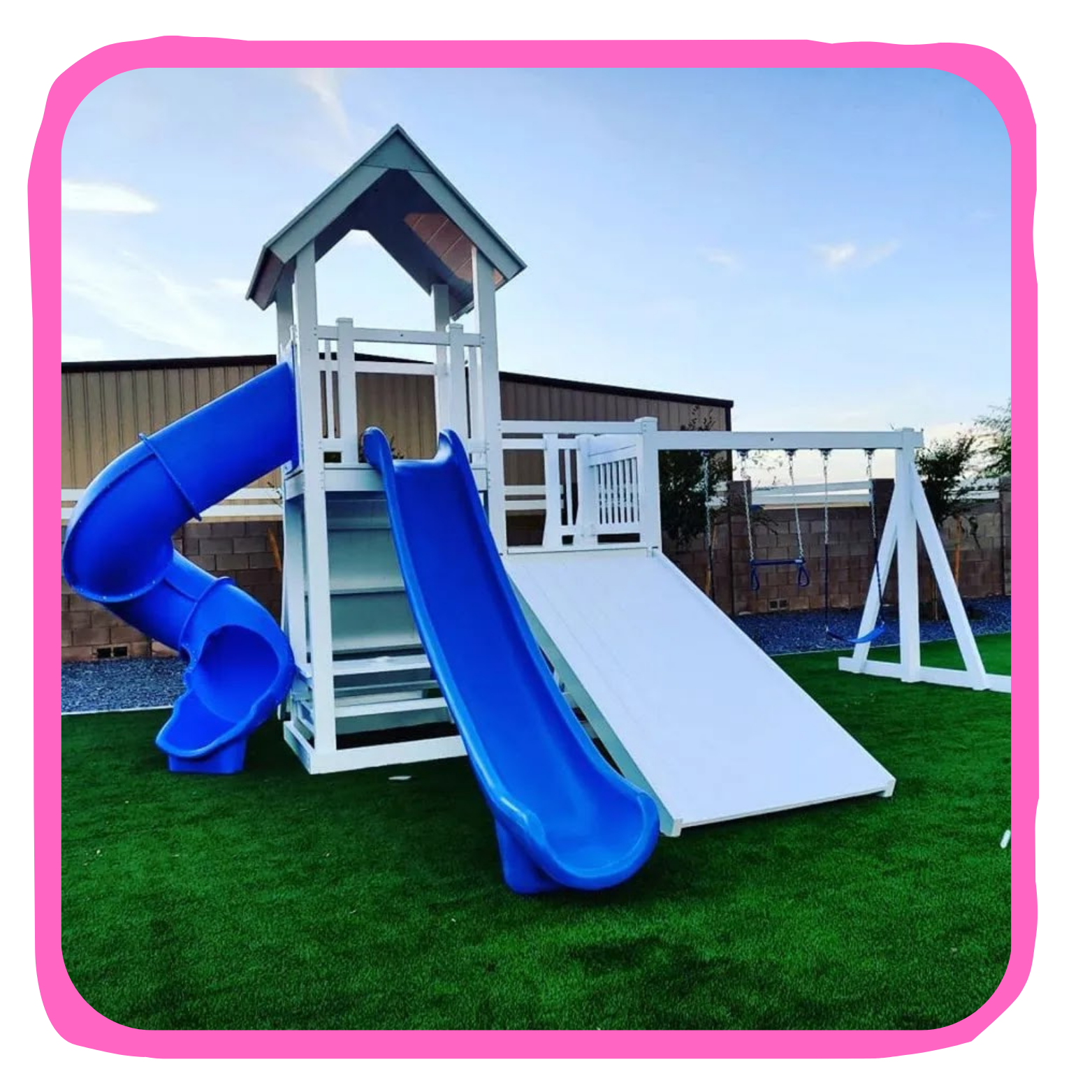 Children's outdoor playground with a white wooden play structure, two blue slides, a small covered tower, and two swings on a grassy surface.