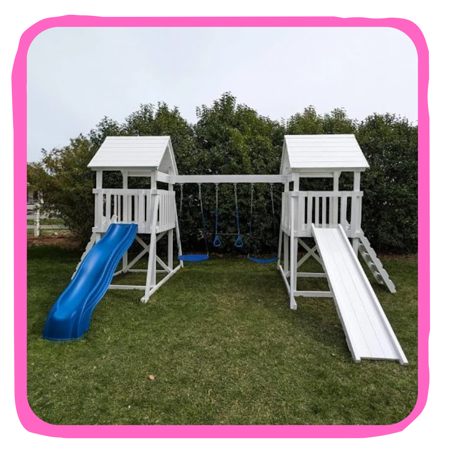 white wooden playset with two towers, blue slide, swings, and ladder on grass