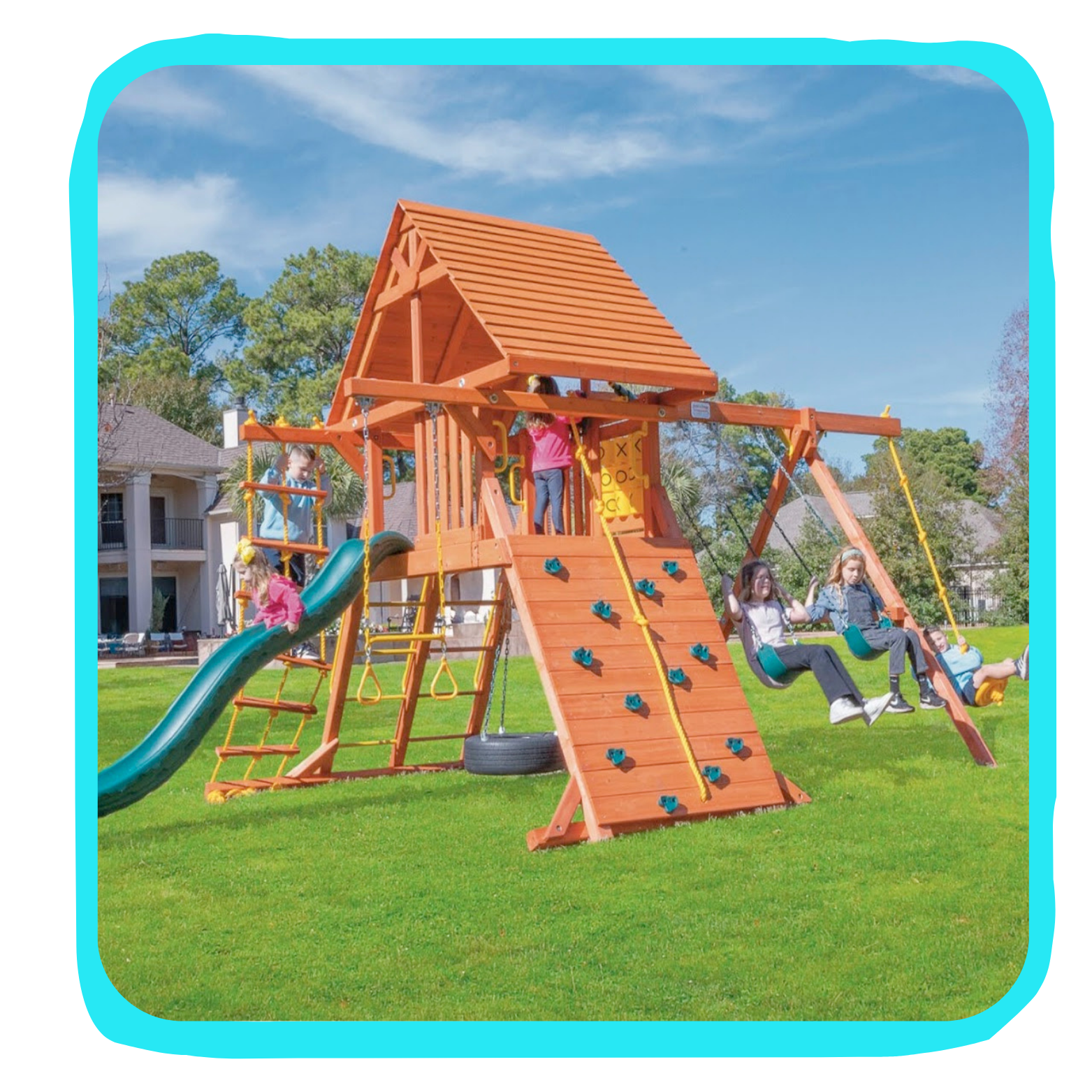 Children playing on a wooden playground set with slides, swings, and climbing walls on a grassy lawn under a blue sky.