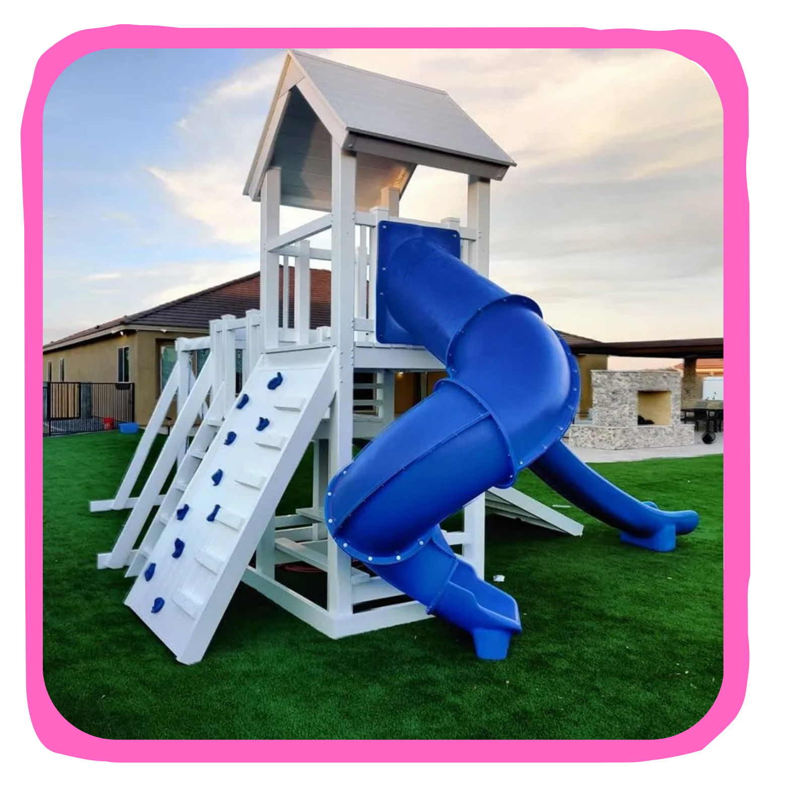 A white wooden outdoor playground structure with a blue spiral slide and climbing wall set on a grassy yard.