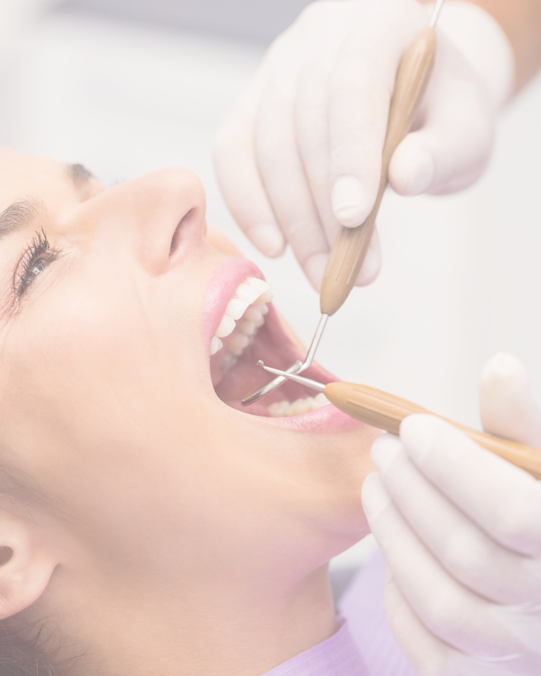 A woman receiving dental treatment, lying back with her mouth open, while a dentist or dental hygienist uses dental tools.