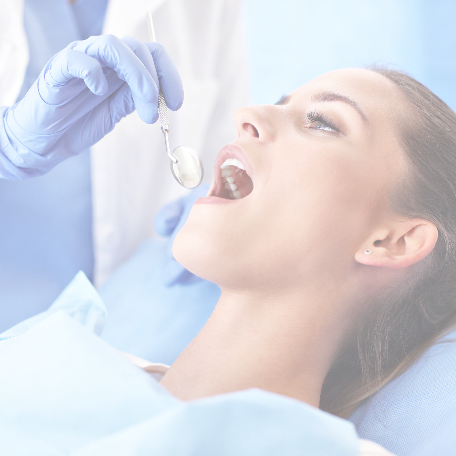 A young woman at the dentist with her mouth open while the dentist, wearing gloves, uses a dental mirror.