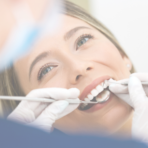 Close-up of a woman receiving a dental checkup, with a dentist examining her teeth.