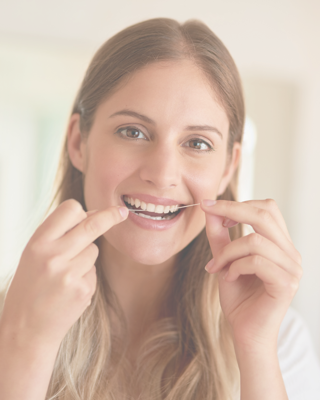 A woman smiling while flossing her teeth.