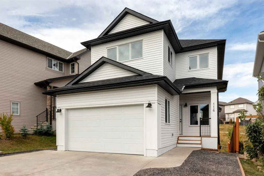 Two-story modern house with vinyl siding, black roof, attached garage, small front porch, and steps leading to front door in a residential neighborhood.