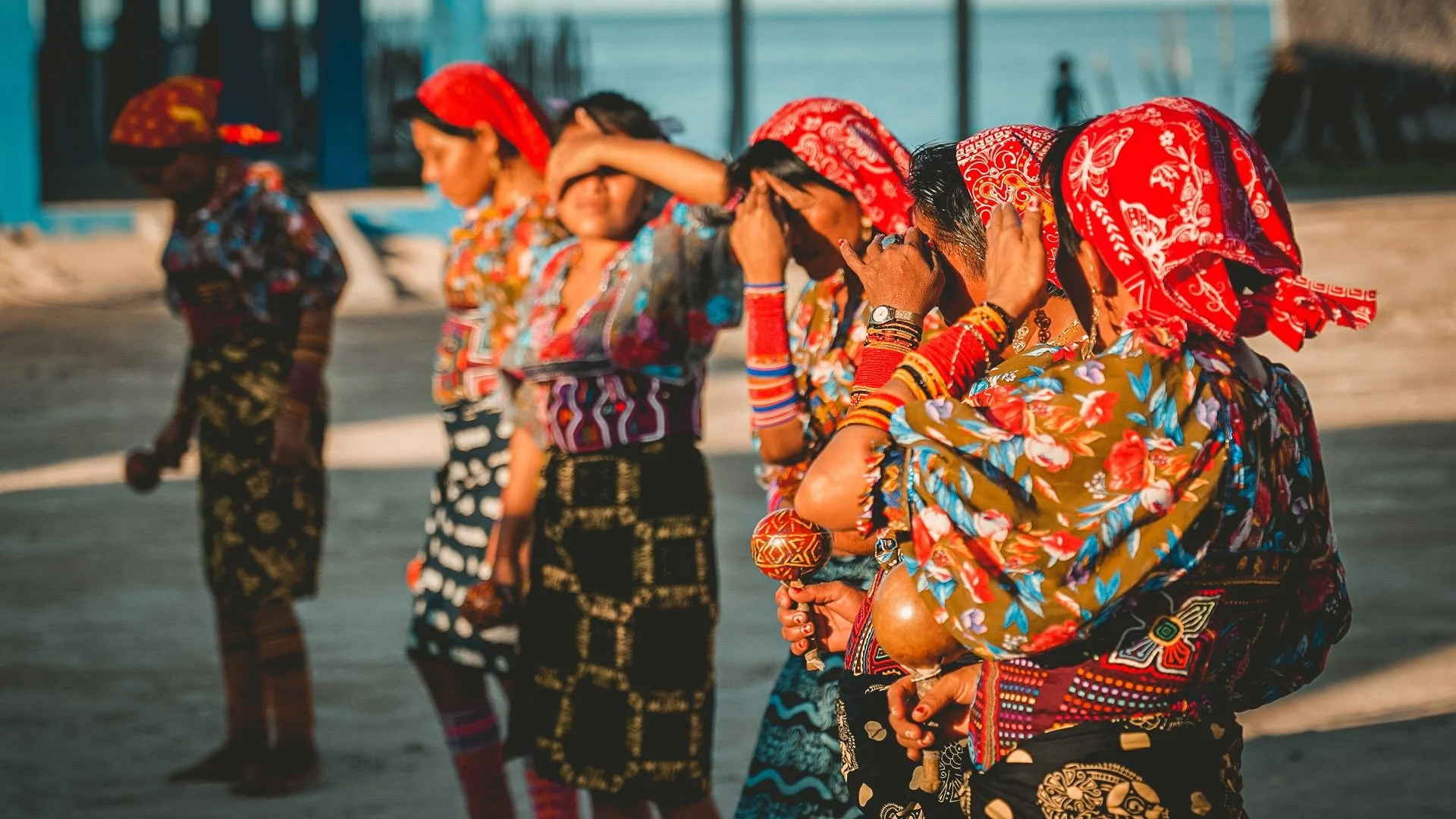Group of women dressed in colorful traditional clothing and headscarves, standing outdoors, participating in a cultural or religious activity.