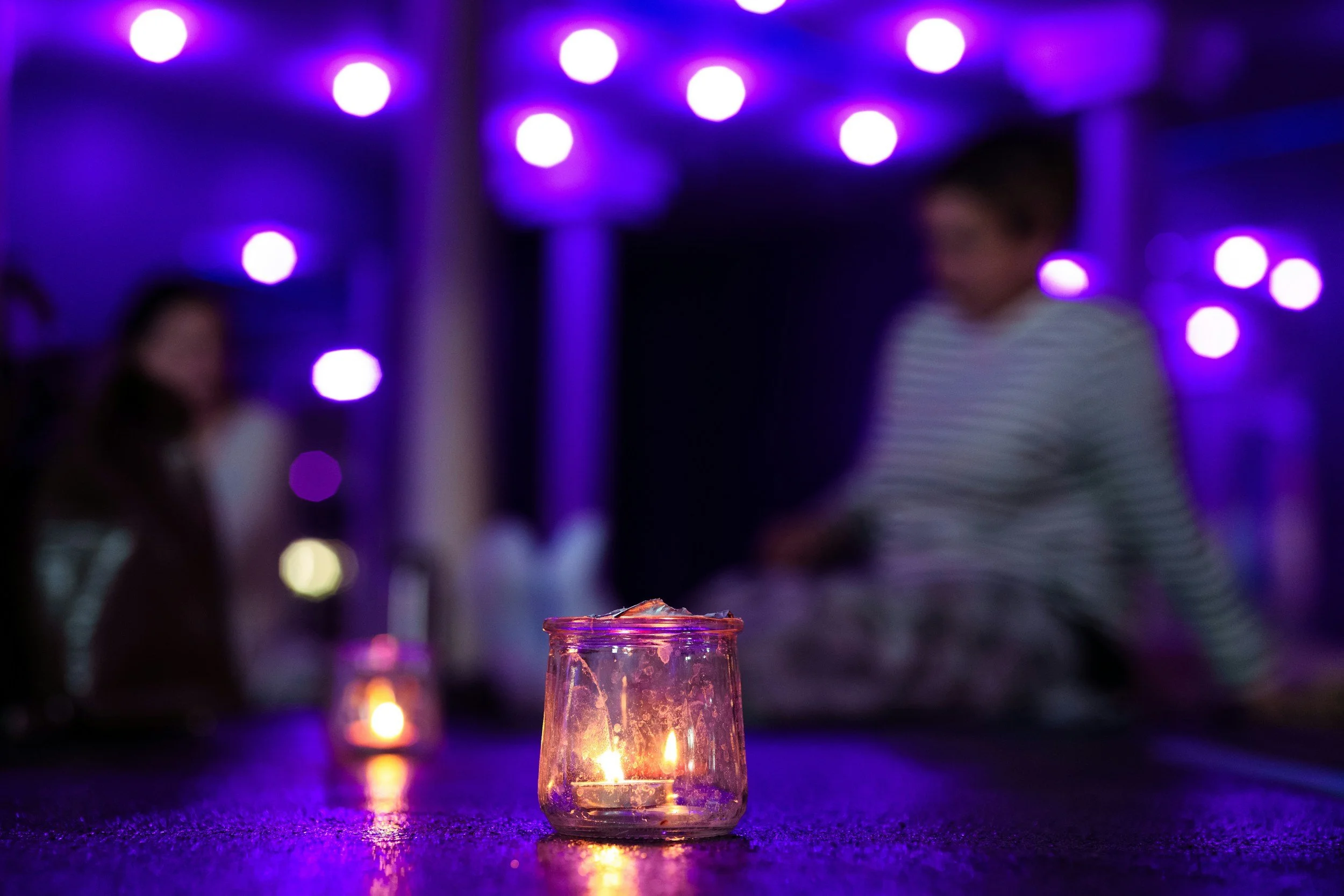 Candle in the foreground with residents participating in a yoga class in the background.