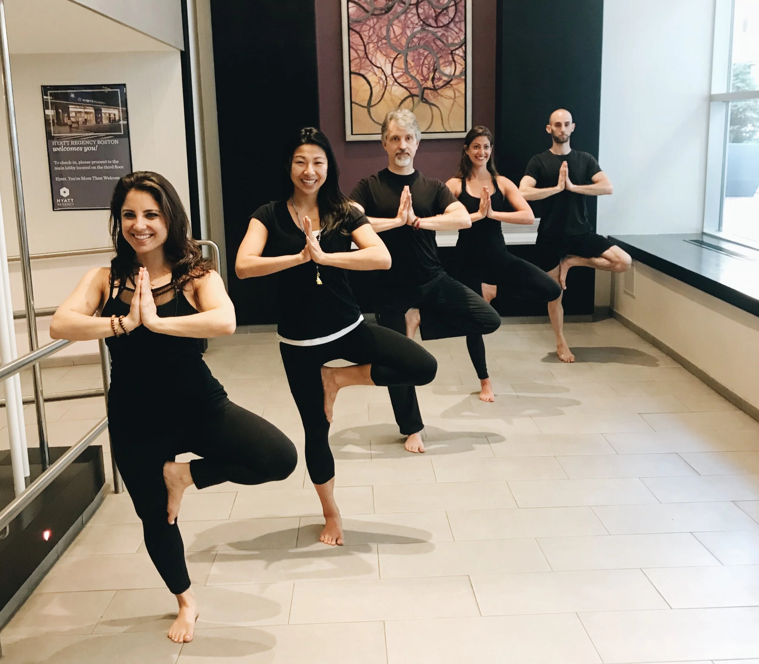 ThriveHub Pros practicing tree pose in a hotel entryway for an onsite hotel wellness program.