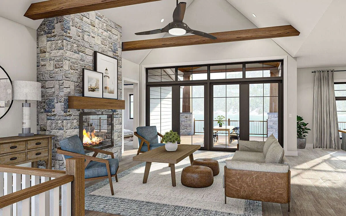 Living room with stone fireplace, wooden beams, ceiling fan, large windows, and sliding glass door leading to outdoor patio with furniture.