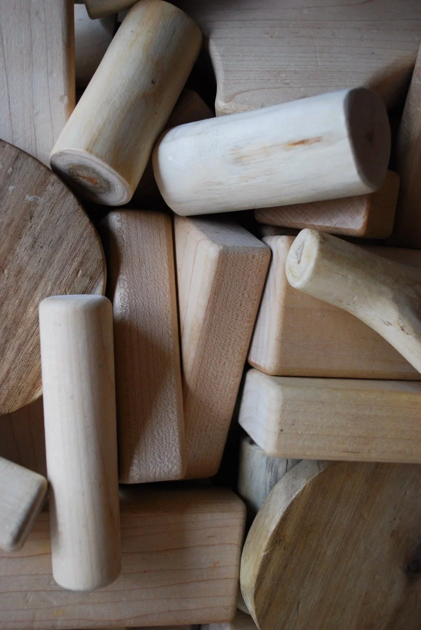 Assorted pieces of unfinished natural wood with various shapes and sizes, some rounded and some rectangular.