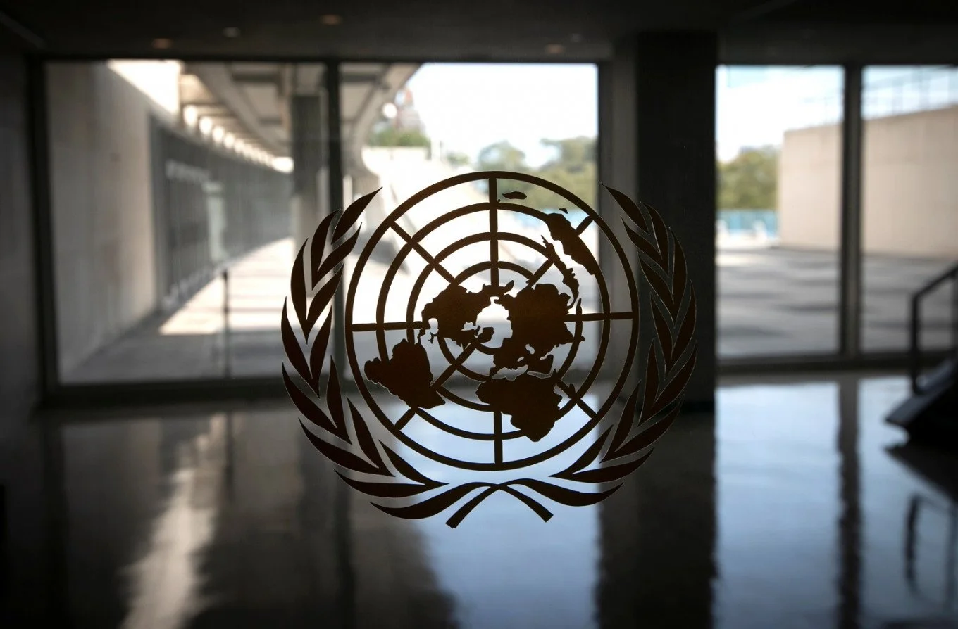 United Nations emblem on glass door in a modern indoor setting.