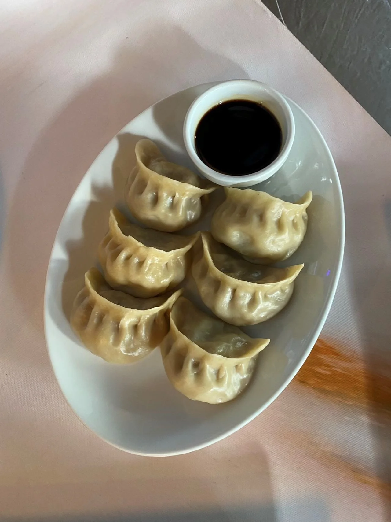 Plate of steamed dumplings with soy sauce in a small cup