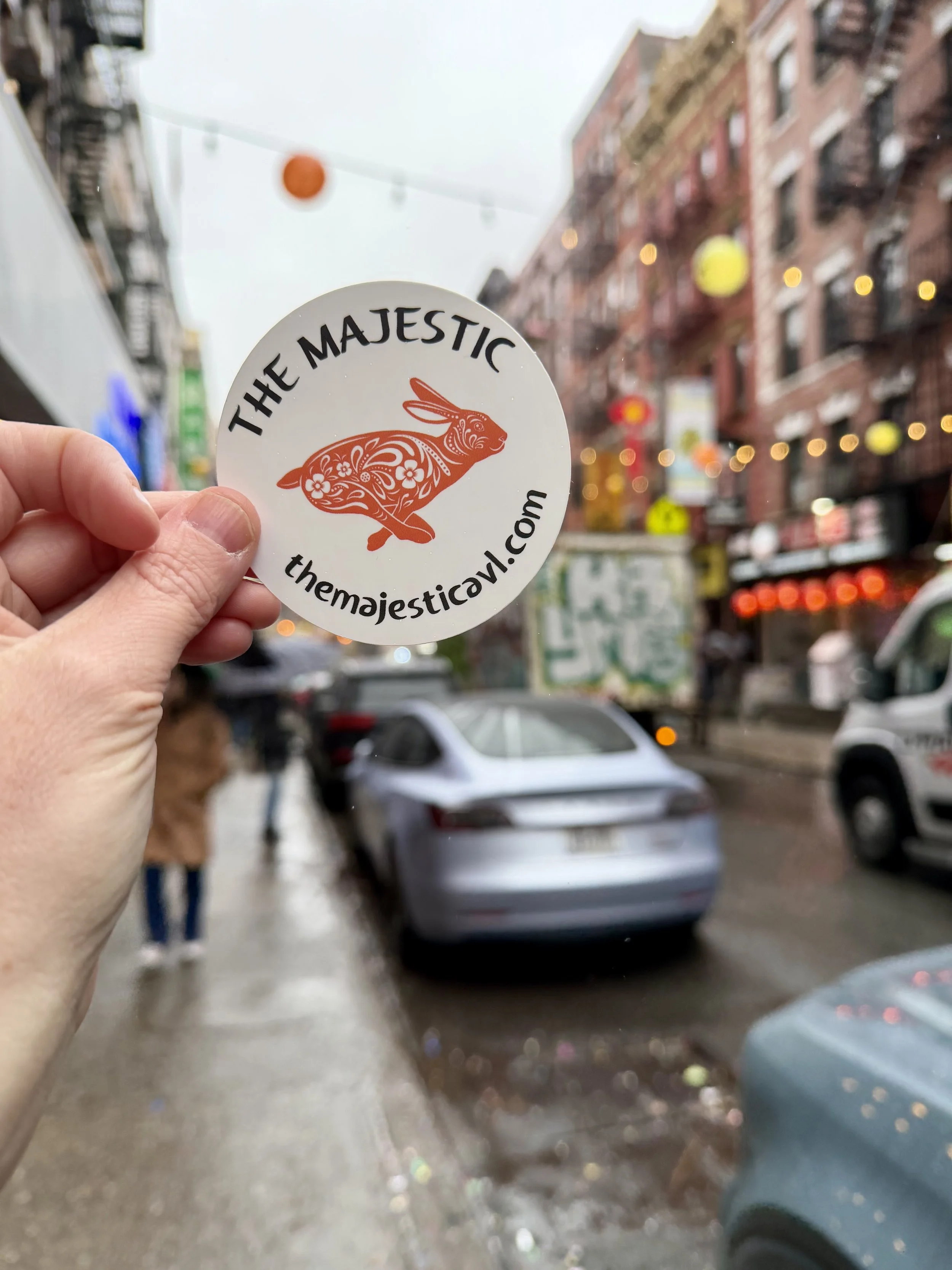 hand holding a The Majestic sticker on Mott Street