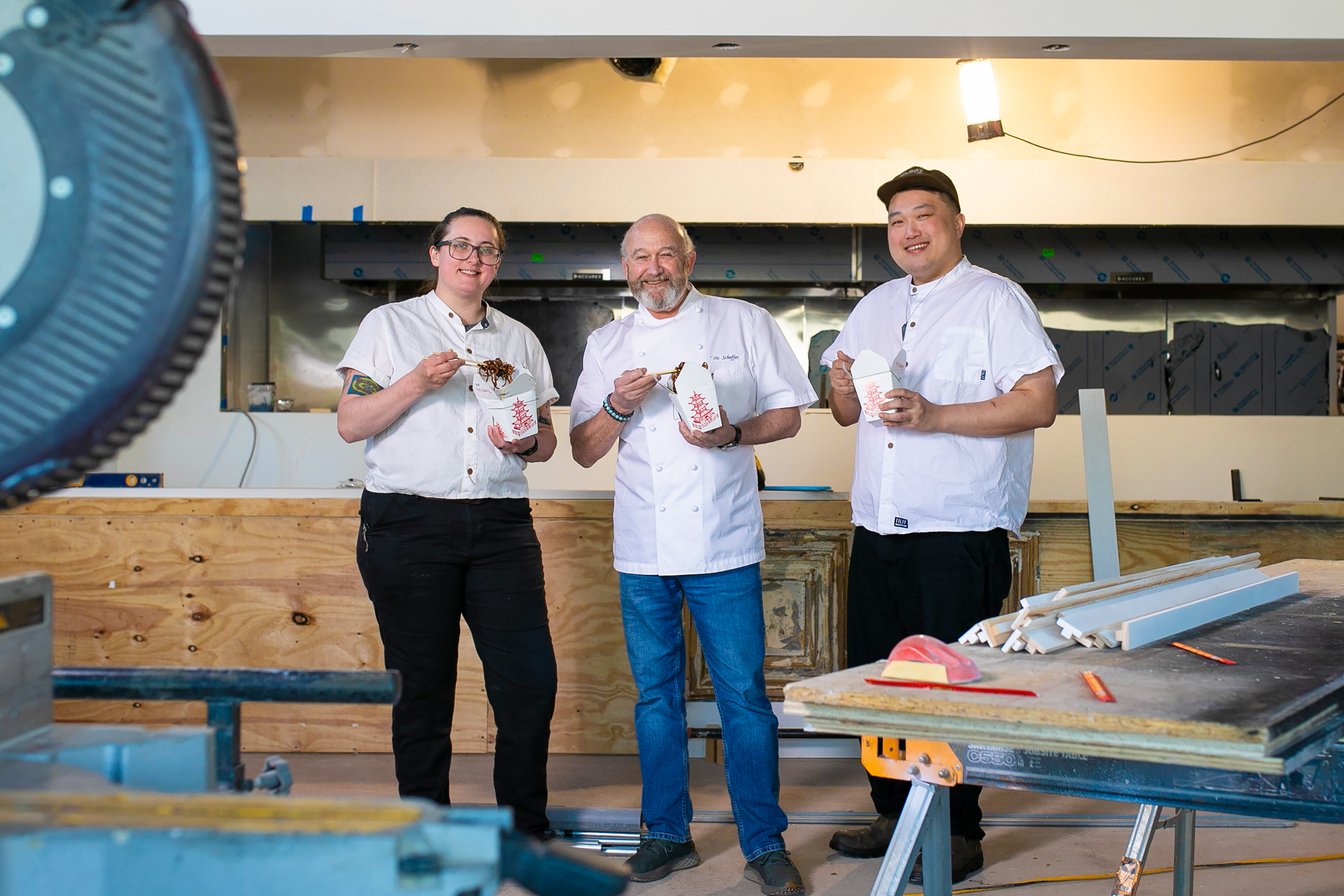 chefs standing in construction eating chinese food