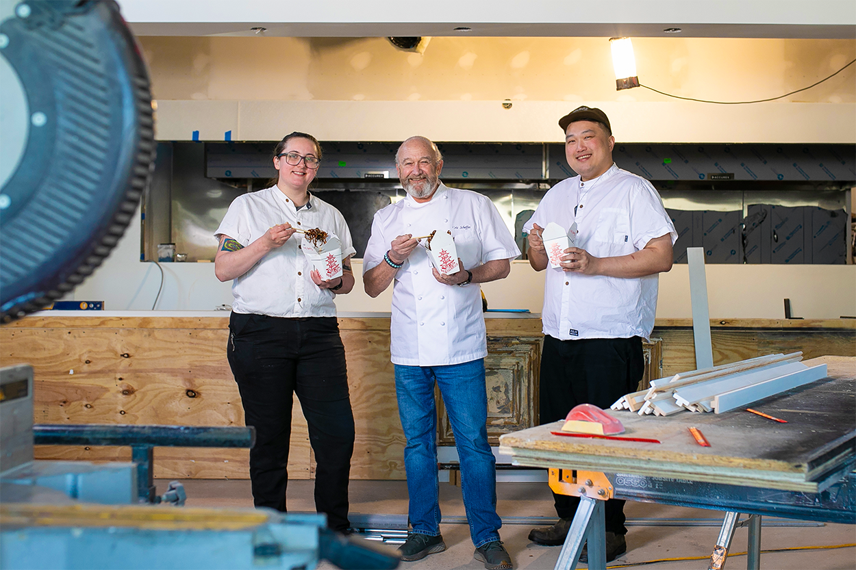 chefs kaya,eric, and ray standing in construction and holding pagoda boxes