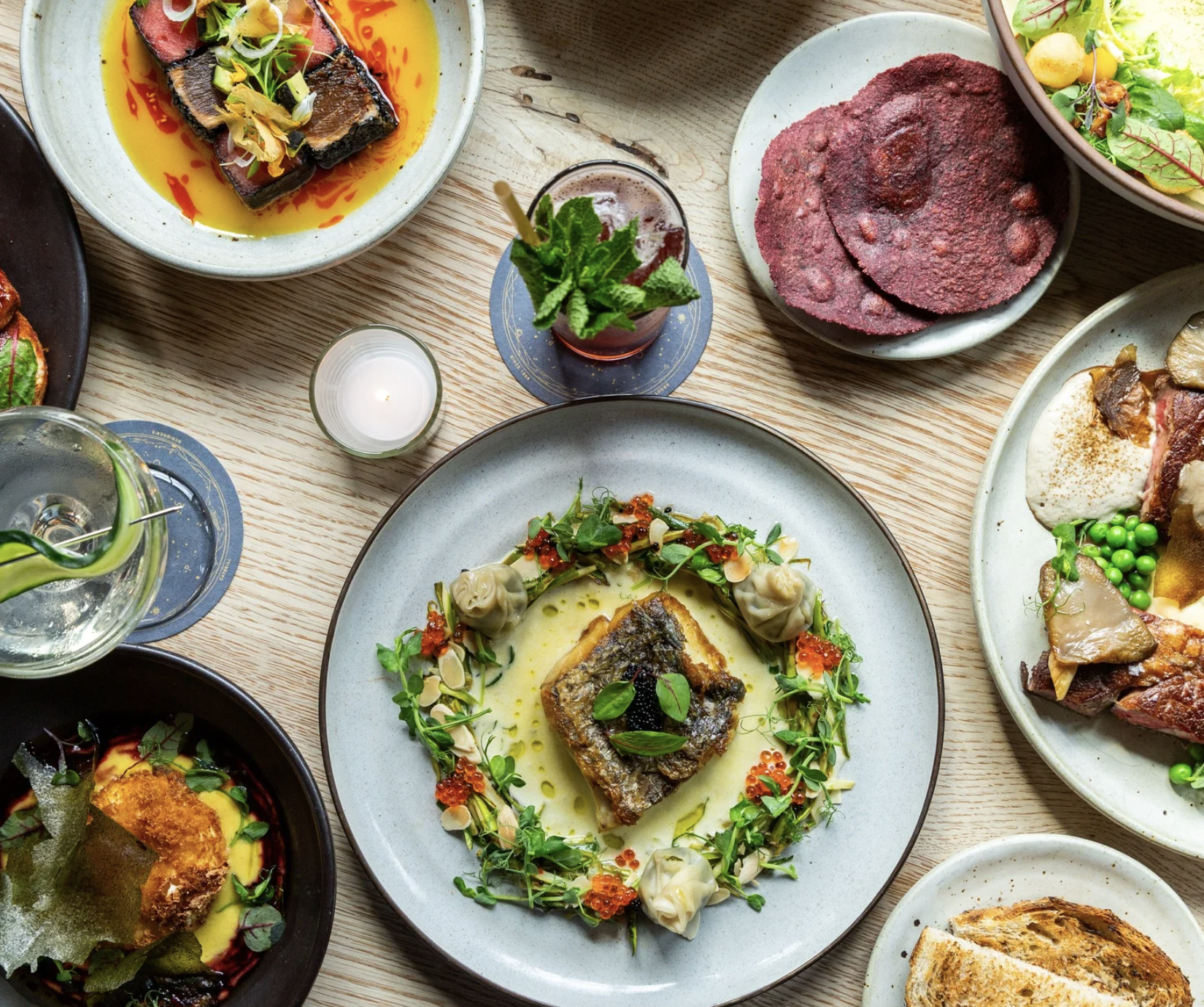 Close-up of a serving dish filled with seasoned, roasted potatoes garnished with fresh herbs at a buffet table.