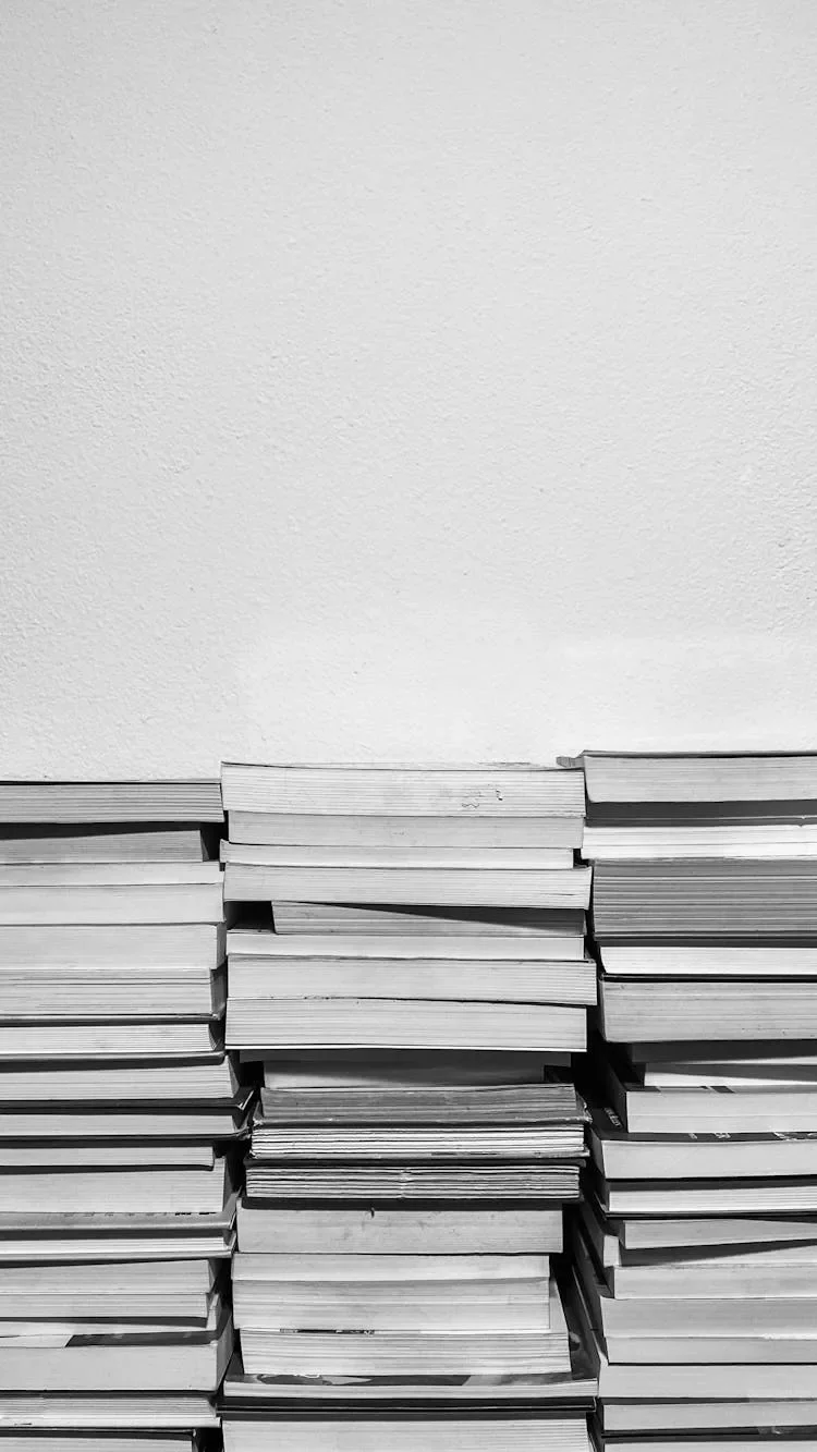 Stacked books arranged horizontally against a white wall.