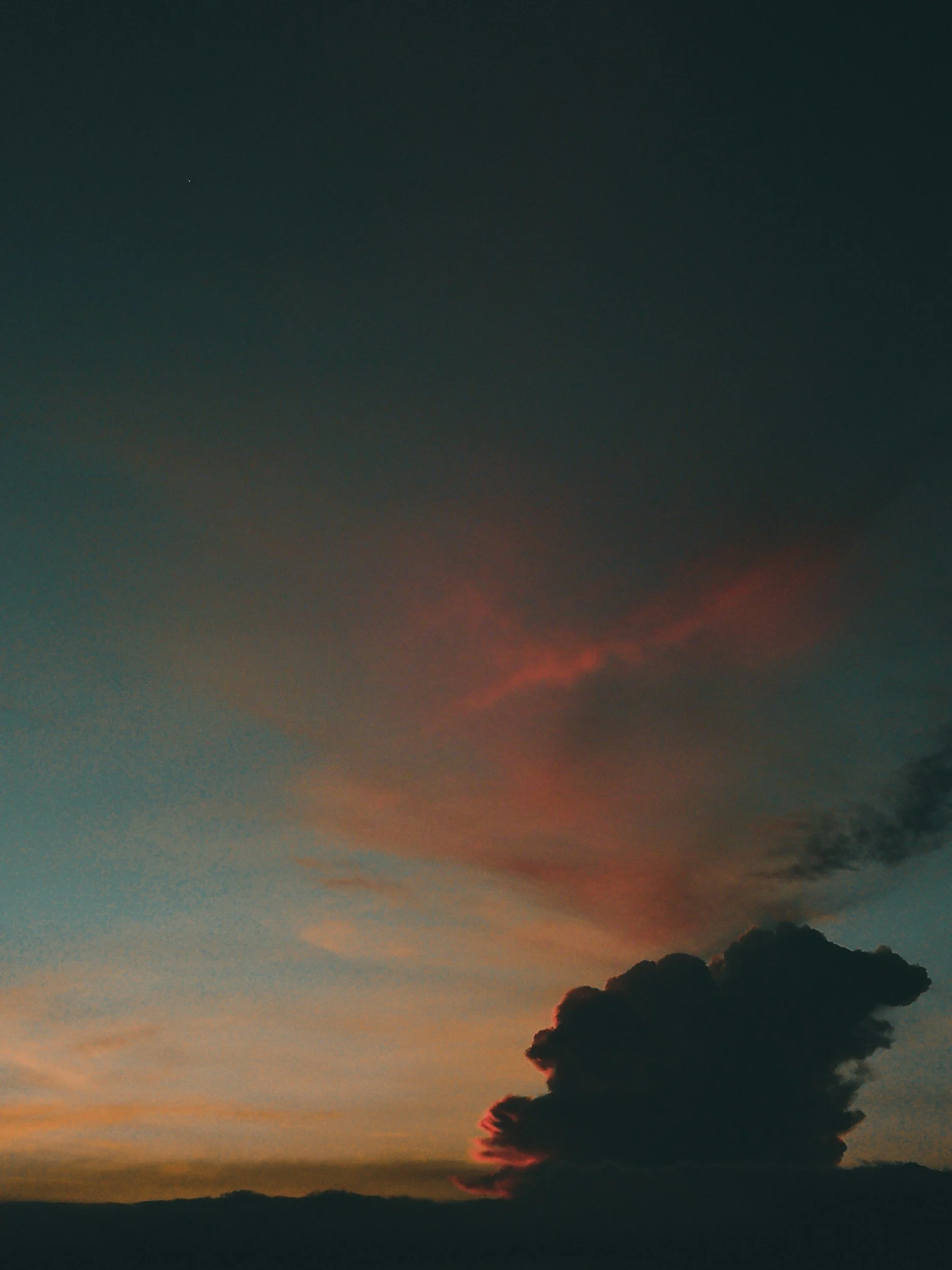 A sunset sky with a dark cloud and orange-pink hues.