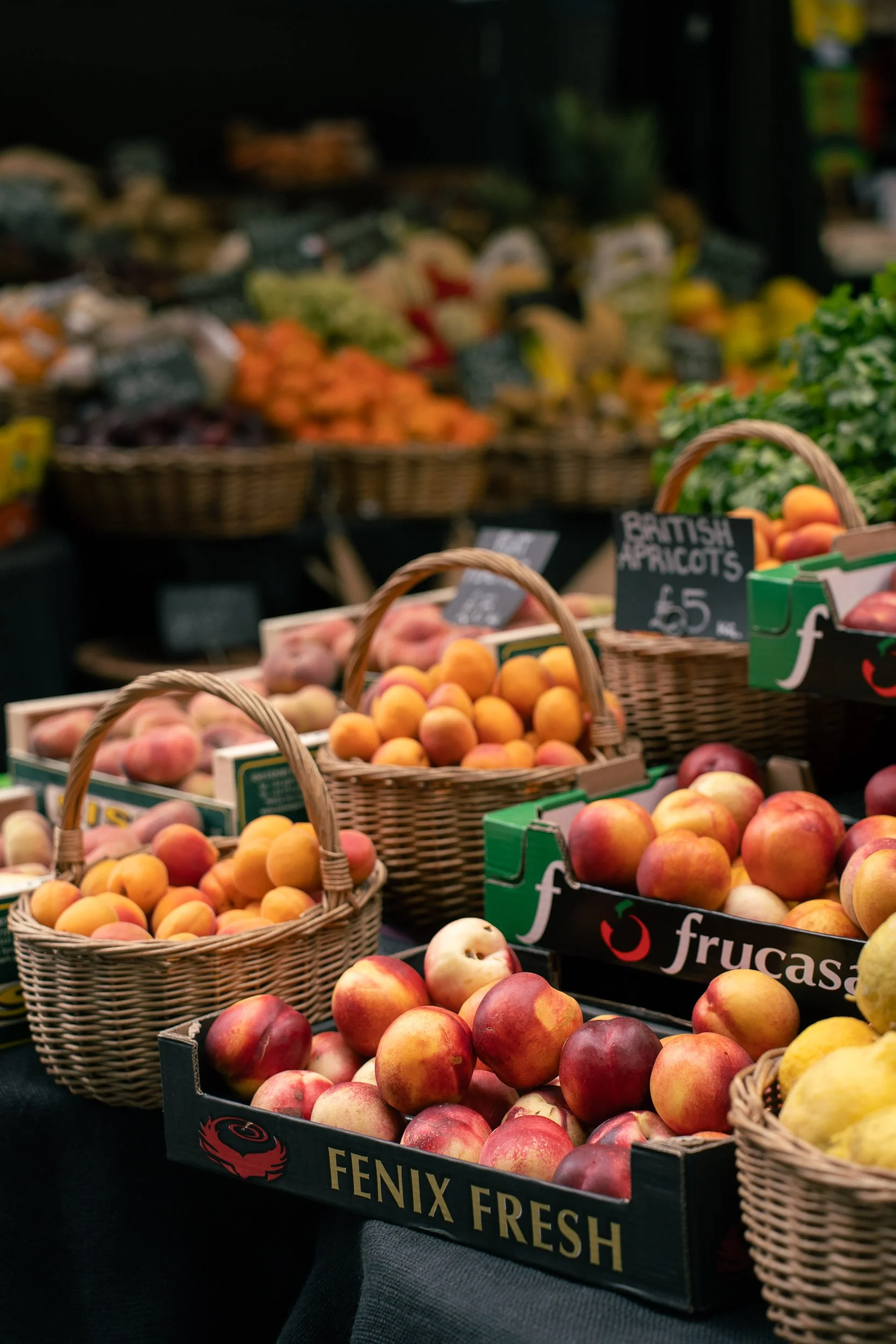 Fresh peaches displayed in crates and baskets at a produce market.