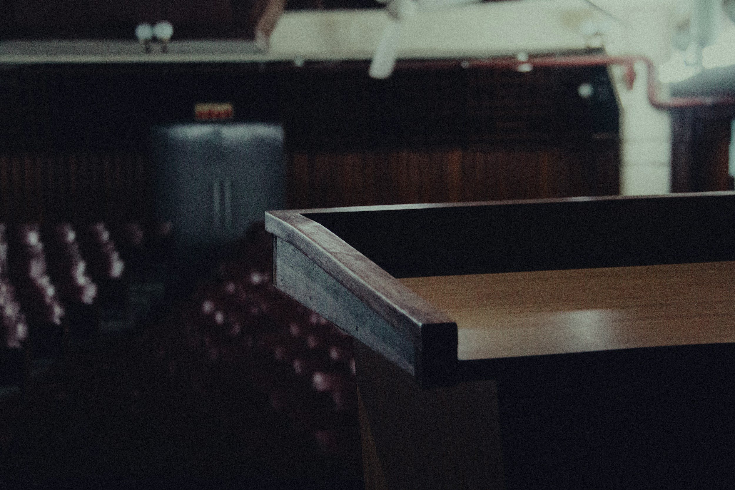Part of a podium with the edge visible, against a dark background of a courtroom.