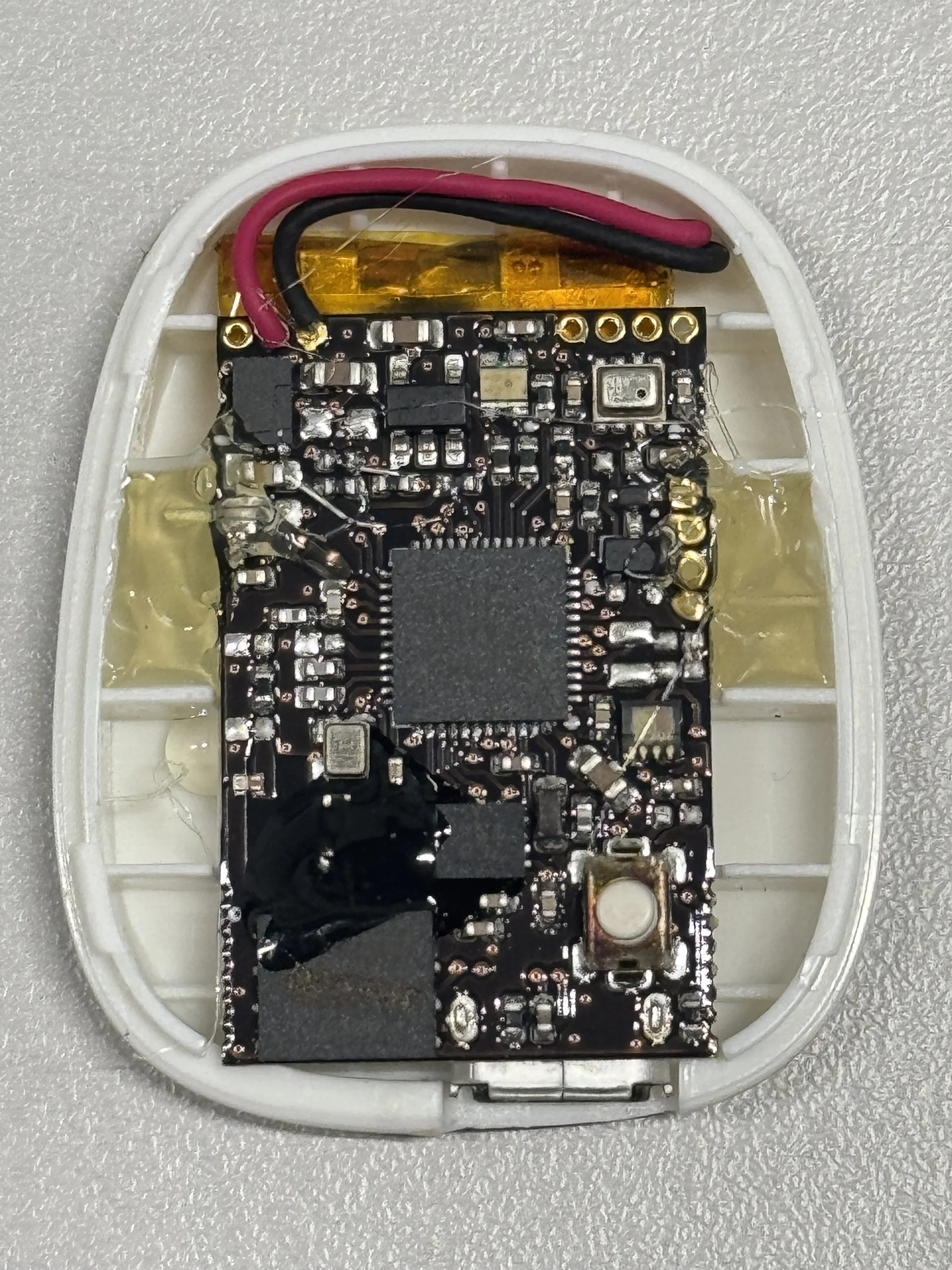 Close-up of a sports shoe with various markers and labels indicating electrical and positional sensors. The shoe is positioned on a green indoor sports court with colored lines.