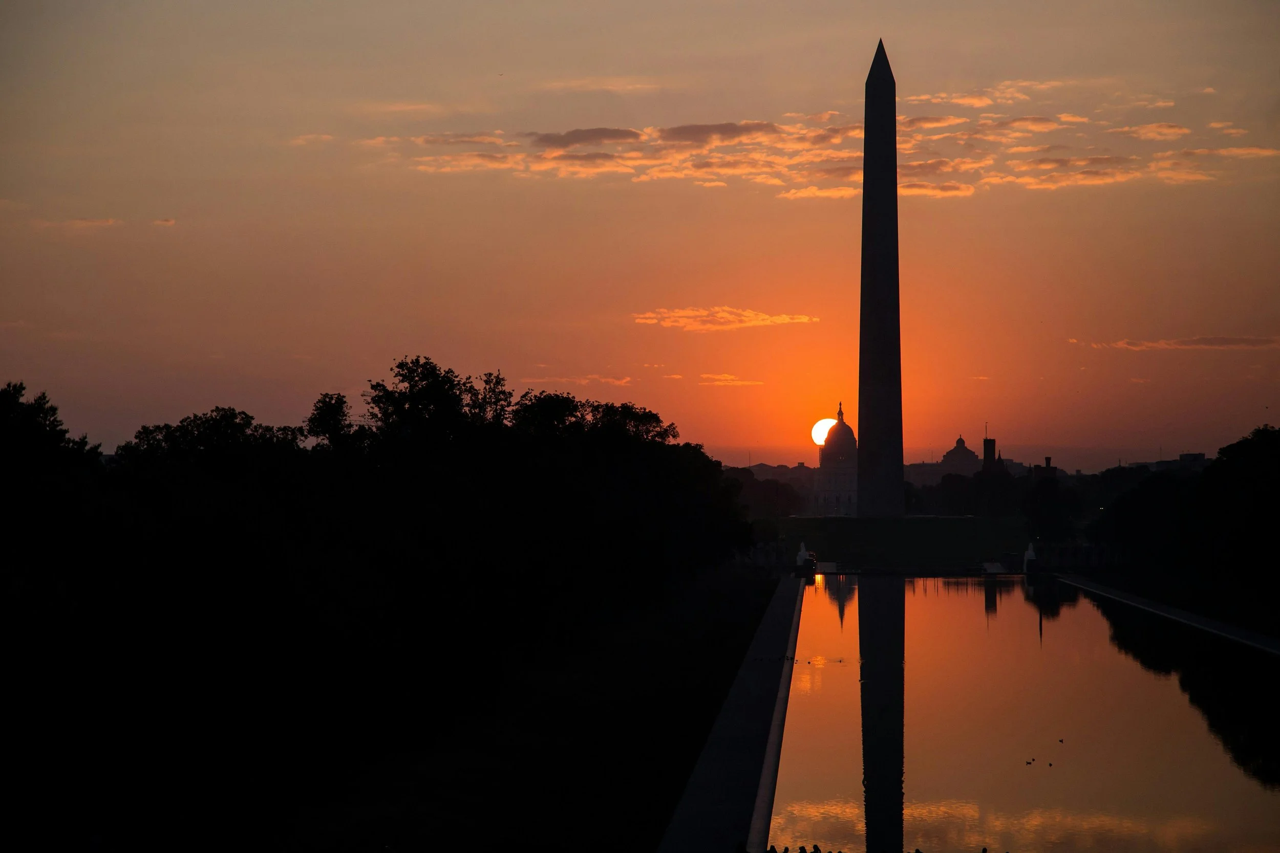 Sunset behind the Washington Monument in Washington, D.C., with reflections in the reflecting pool.