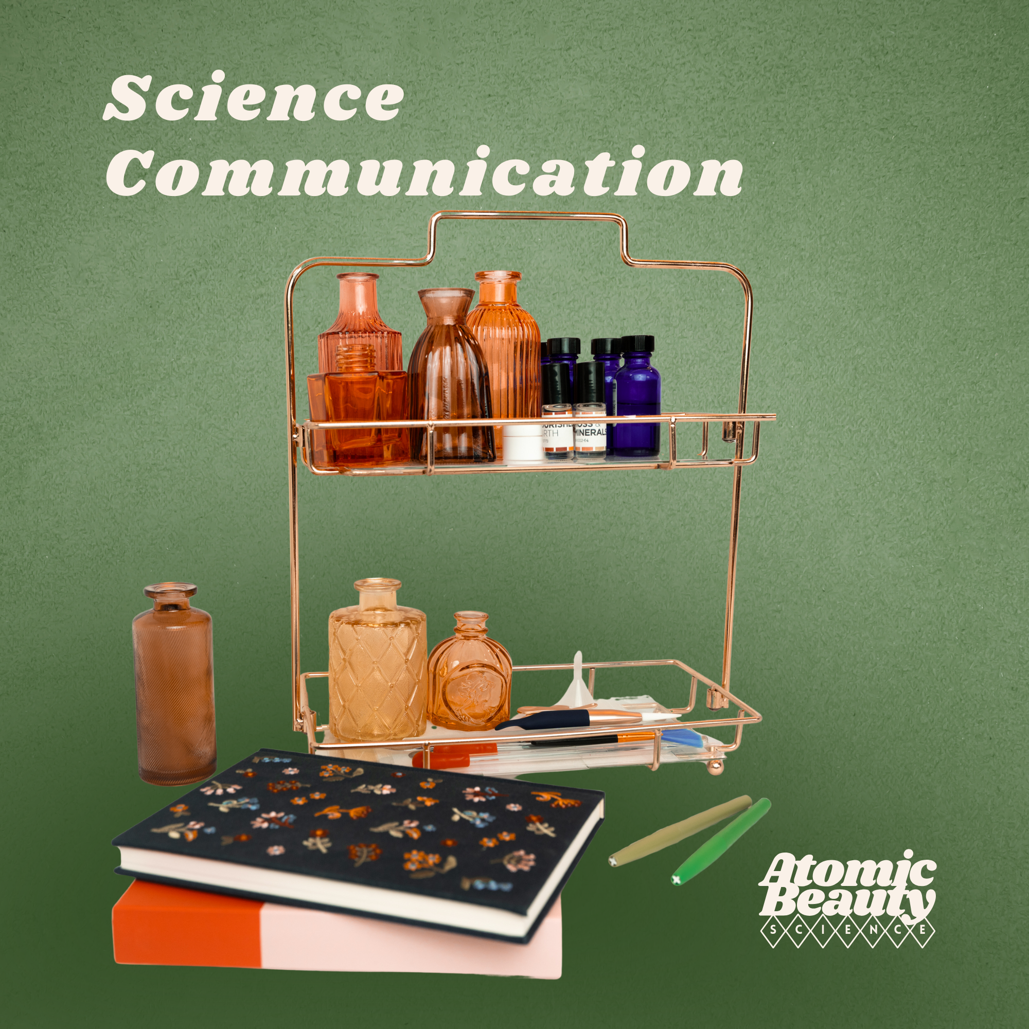Stationery and bottles on a green background with the text 'Science Communication' and 'Atomic Beauty Science'.