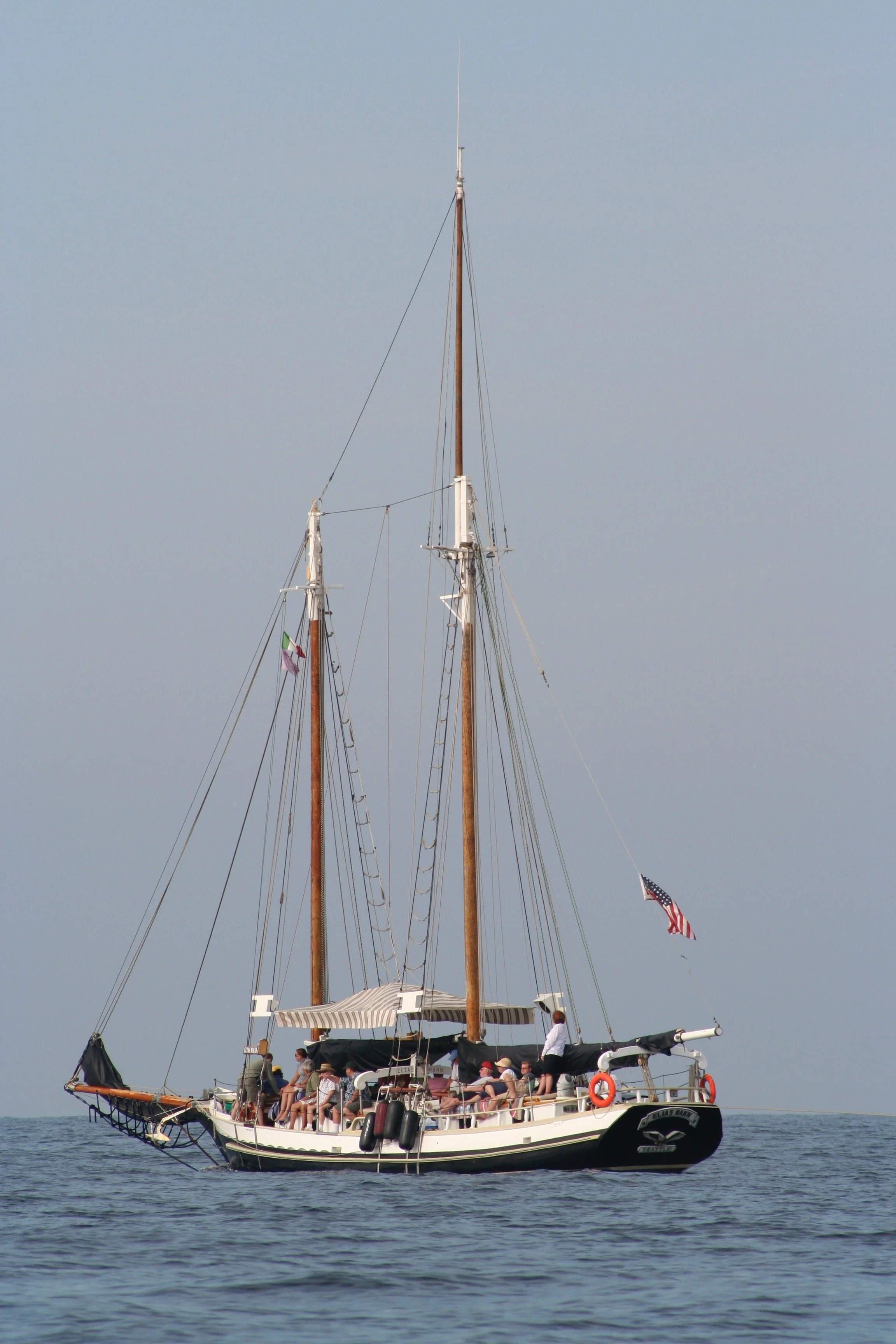 A sailboat on calm water with people on deck and American flags.