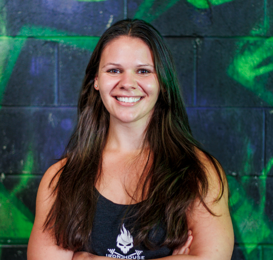 Woman with long brown hair smiling in front of a graffiti wall.
