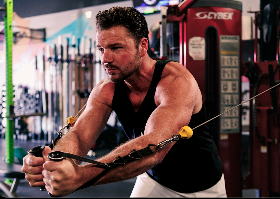 A man exercising with resistance bands in a gym.