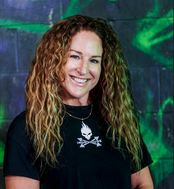 smiling woman with curly red hair standing in front of a graffiti wall