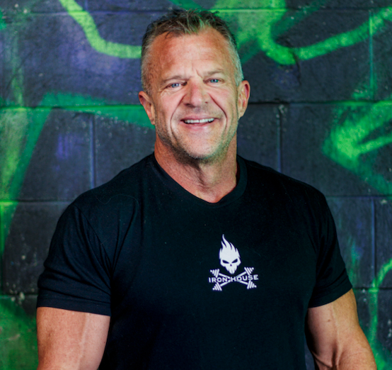 Smiling man with short blonde hair in black Iron House t-shirt standing in front of a graffiti wall.
