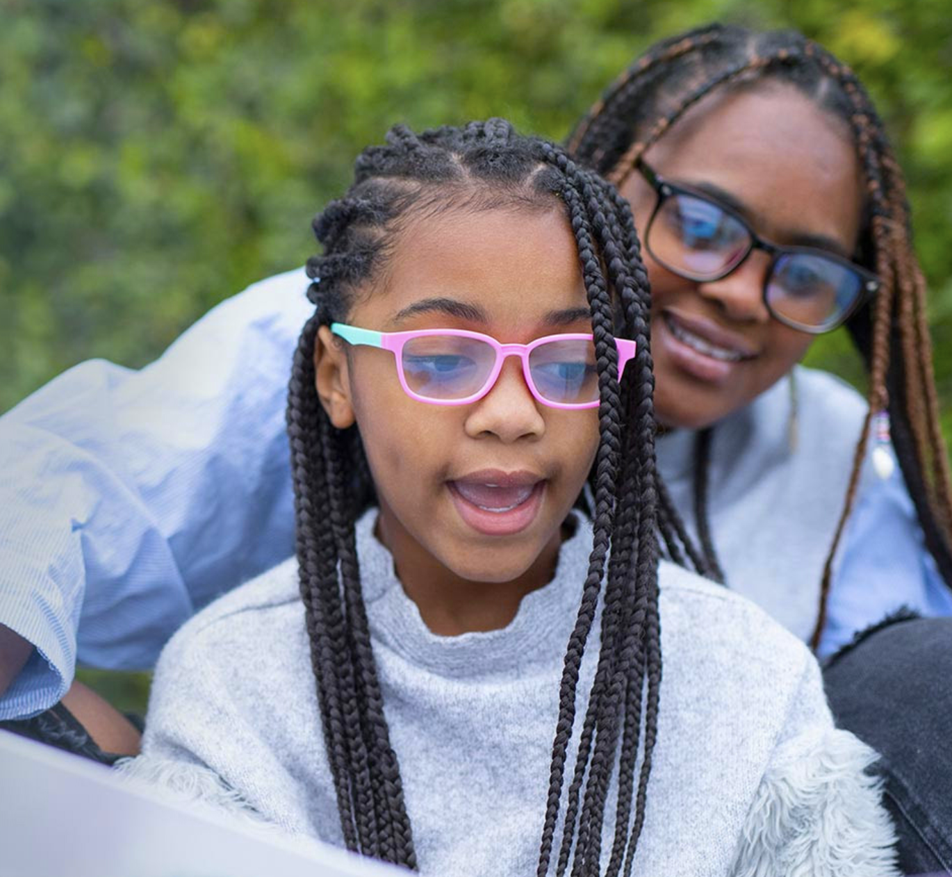 A child reads aloud with her smiling mother